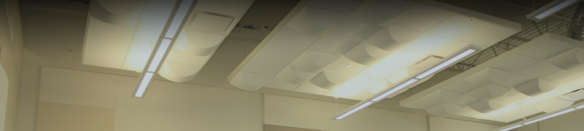 Commercial accoustical ceiling with drop down lights and decorative sound absorbing panels in a high-traffic school area