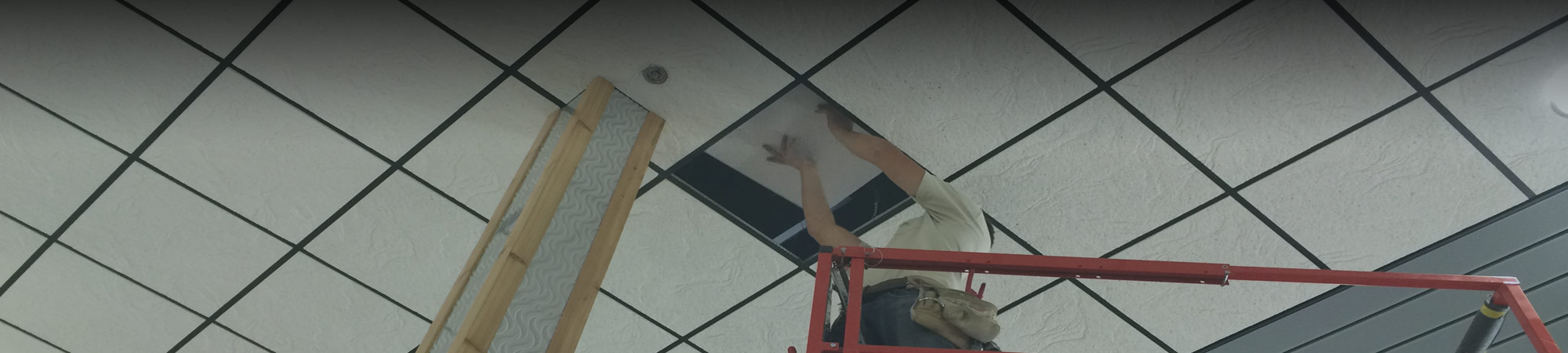 A crew member of Central Suspensions installing a commercial accoustical tiled ceiling in a convenience store
